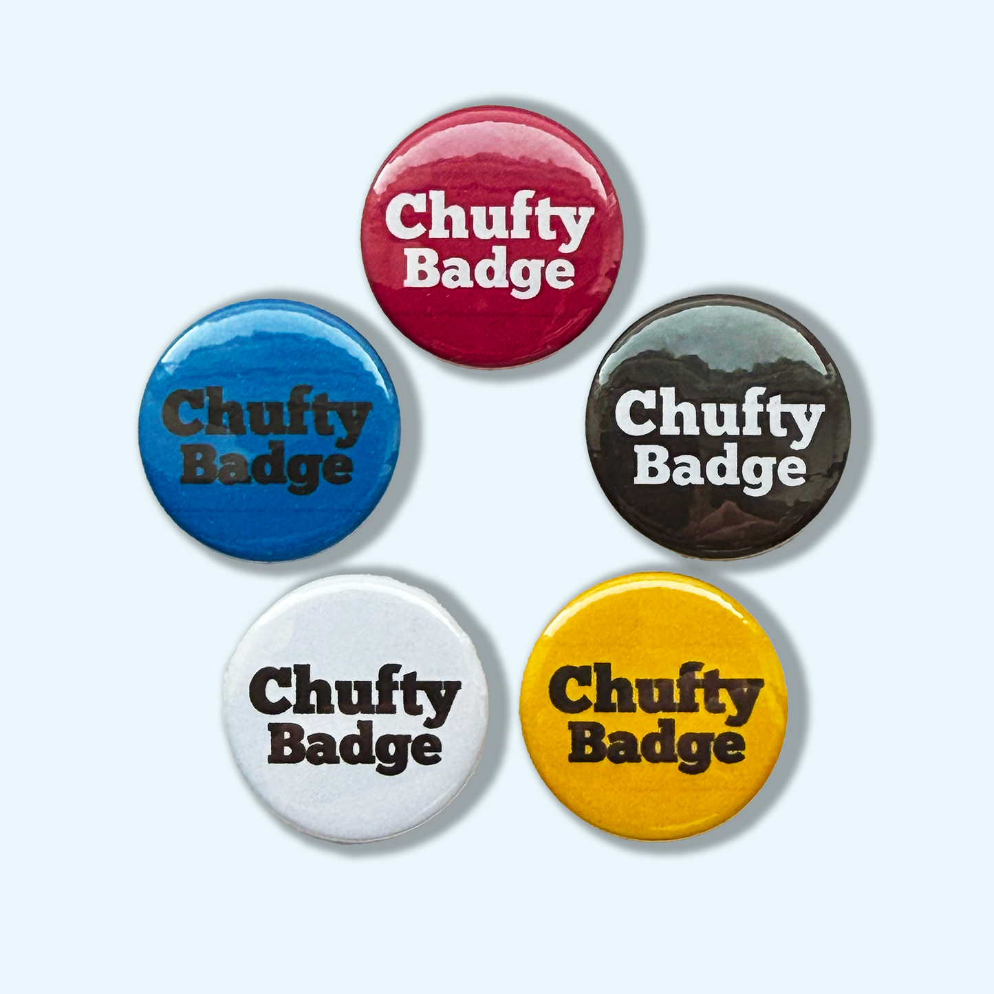 Set of five colorful buttons with 'Chufty Badge' text on a white, Blue, magnenta, black,and yellow background
