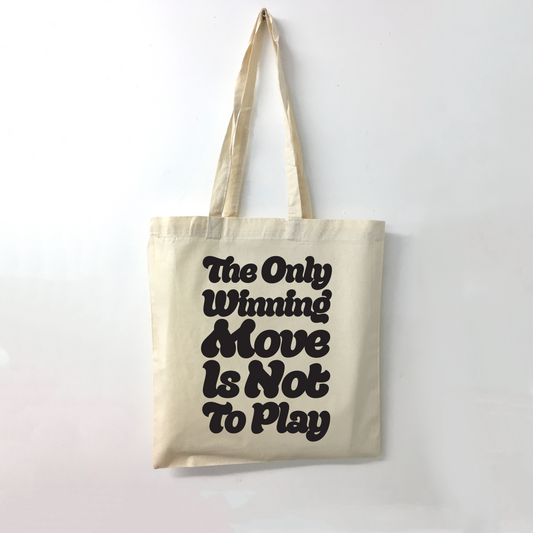 Beige tote bag with black The Only Winning Move Is Not To Playt ext on a white background