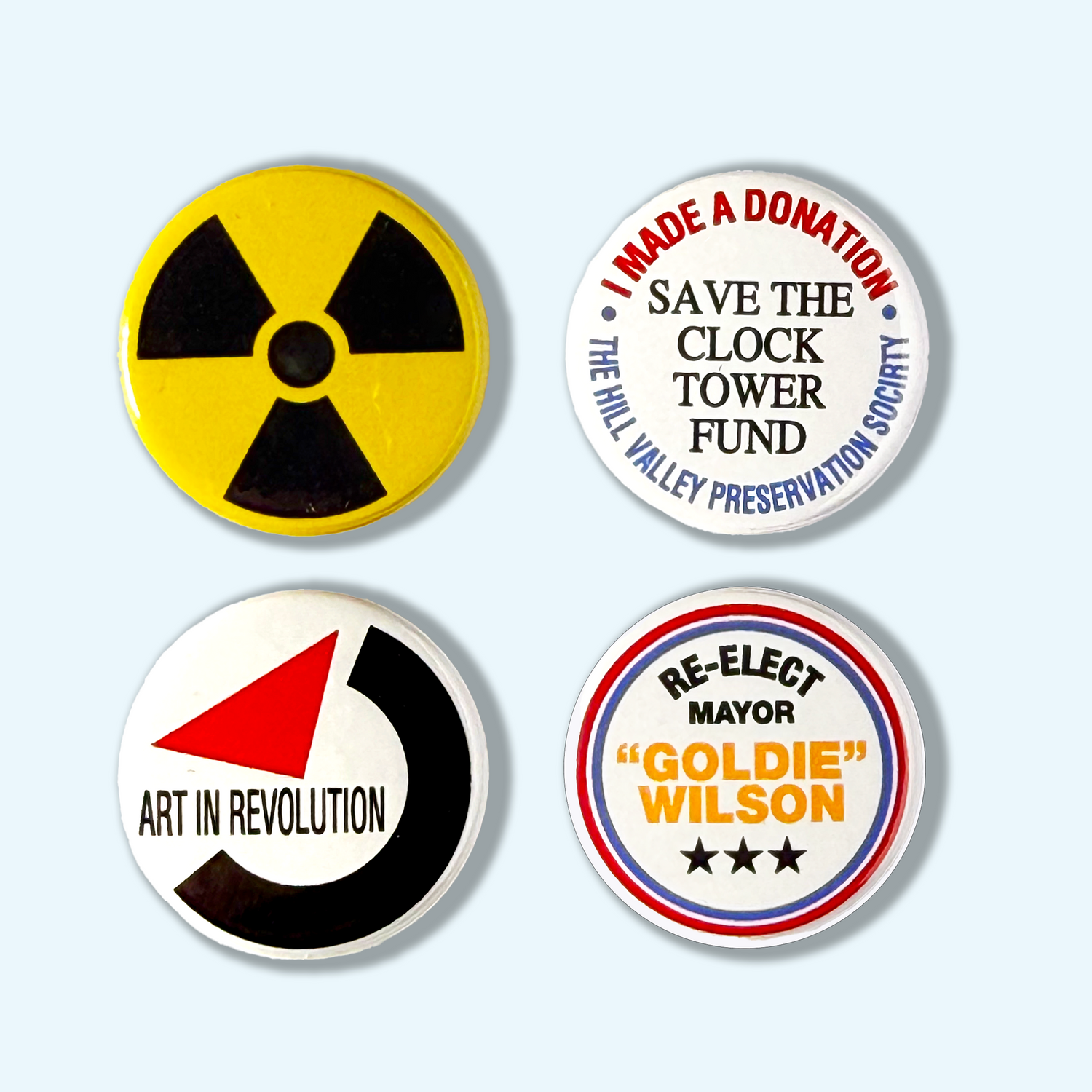 Four Back to the Future button badges with different designs and text on a light blue background