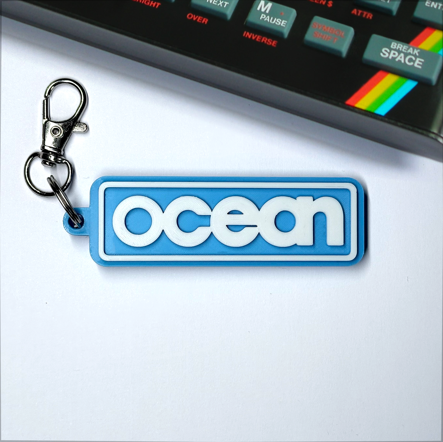 Blue 'ocean' keychain with a vintage Spectrum 48k electronic device in the background